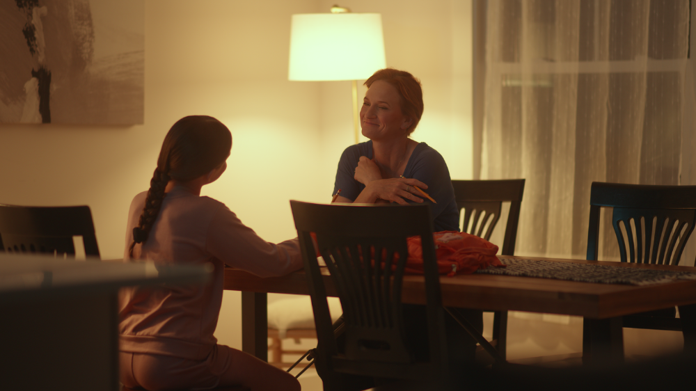 Mother and daughter sitting at dinner table.